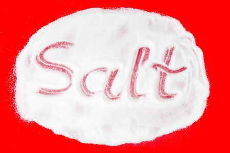 Word salt written into a pile of white salt on red backgroundの写真素材