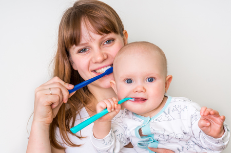 Mother and her baby brushing teeth together in the morning - dental care conceptの写真素材