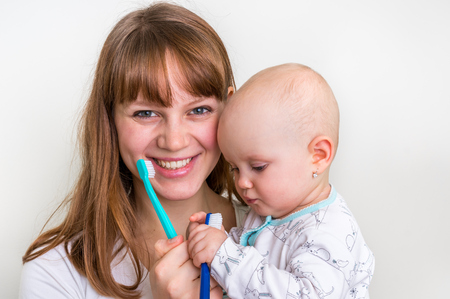 Mother and her baby brushing teeth together in the morning - dental care conceptの写真素材