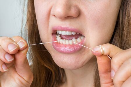 Woman cleaning teeth with dental floss - hygiene and healthy teethの写真素材