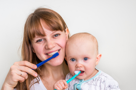 Mother and her baby brushing teeth together in the morning - dental care conceptの写真素材