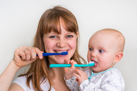 Mother and her baby brushing teeth together in the morning - dental care conceptの写真素材