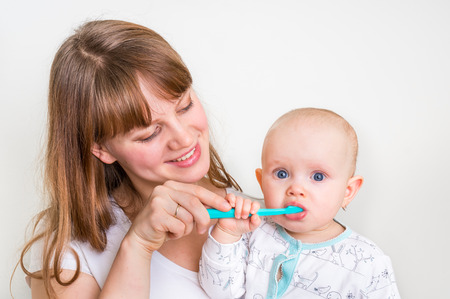 Mother and her baby brushing teeth together in the morning - dental care conceptの写真素材