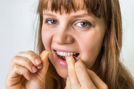 Woman cleaning teeth with dental floss - hygiene and healthy teethの写真素材