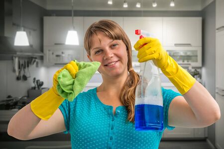 Young smiling housewife woman cleaning kitchen at homeの写真素材