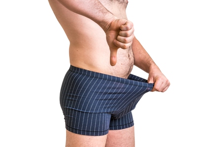 Attractive man is looking in his boxer underwear and pointing thumb down - impotence conceptの写真素材