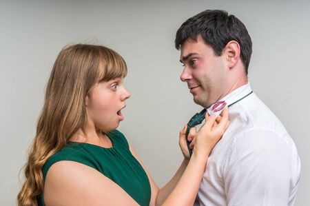 Aggressive wife revealed red lipstick on shirt collar of her unfaithful husband - infidelity conceptの写真素材