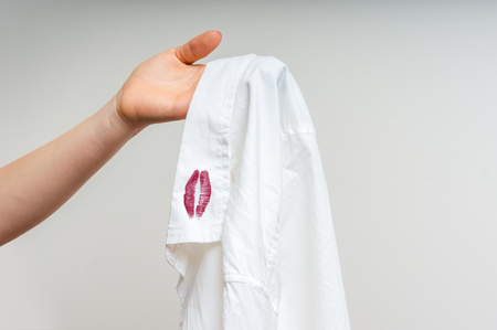 Woman holding a shirt with red kiss lipstick of her unfaithful husbandの写真素材