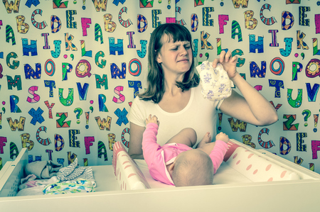 Mother changing smelly diaper to her little baby girl - retro styleの写真素材