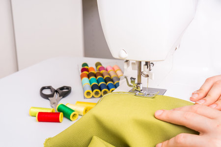 Seamstress is sewing on sewing machine at home