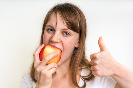Young woman eating an apple isolated on white - healthy diet conceptの写真素材