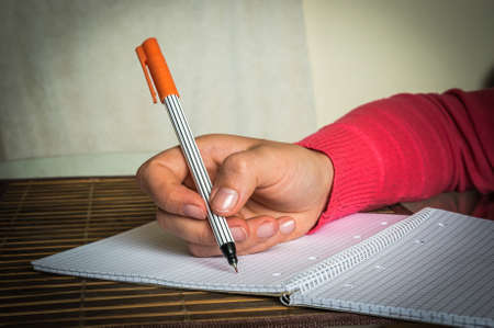 Closeup of female hand writing on the notepadの写真素材