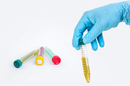 Scientists hand holding a test-tube with green liquid on gray backgroundの写真素材
