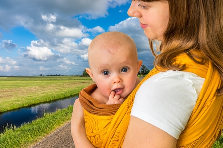 Happy mother with her baby in a sling carrying him in a village in the Netherlandsの写真素材