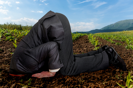 Unsuccessful businessman burying his head in the groundの写真素材