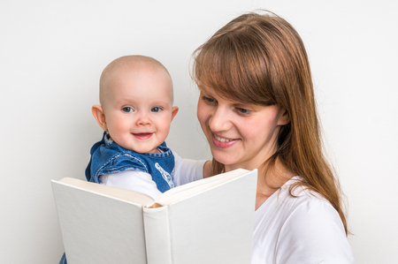Smiling mother and her child reading a book isolated on whiteの写真素材