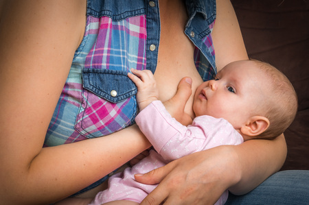 Happy mother breast feeding newborn baby at homeの写真素材