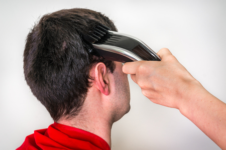 Hairdresser cutting black hair with electric hair clipper in barber shopの写真素材