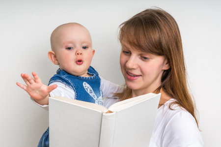 Smiling mother and her child reading a book isolated on whiteの写真素材