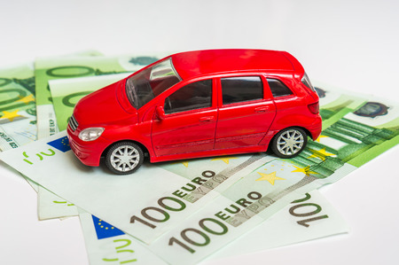 Toy car and euro money banknotes on white - insurance, rent and buying car conceptの写真素材