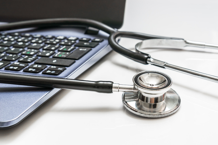 Close-up of stethoscope and laptop computer on white backgroundの写真素材