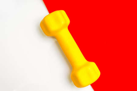 Yellow dumbbell for fitness on creative red and white backgroundの写真素材