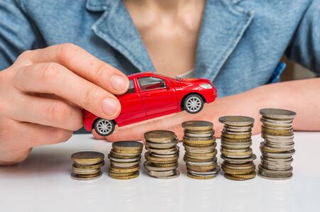 Businesswoman and toy car on coin stack - insurance, loan and buying car conceptの写真素材
