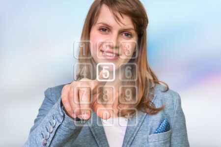 Businesswoman pressing numerical button on virtual touch screen - modern computer controlの写真素材