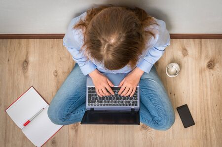 Top view of student is sitting on wood floor with laptop - study and education conceptの写真素材