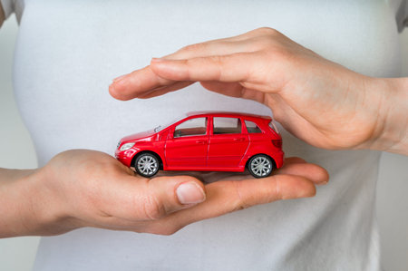 Red car in female hands - insurance, rent and buying car concept