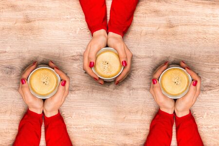 Female hands holding a cup of hot coffee on wooden tableの写真素材