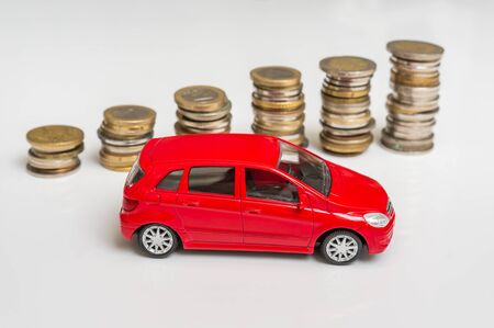 Toy car and coin stack on white - insurance, loan, rent and buying car conceptの写真素材