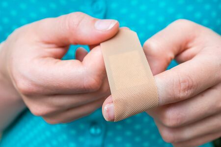 Young woman puts a plaster on her injured fingerの写真素材