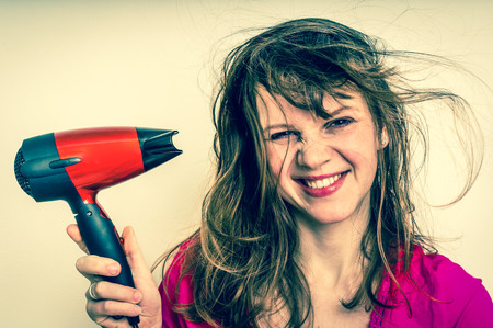 Fashion girl with red hair dryer dries her hair - retro styleの写真素材