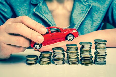 Businesswoman and toy car on coin stack - insurance, loan and buying car concept - retro styleの写真素材