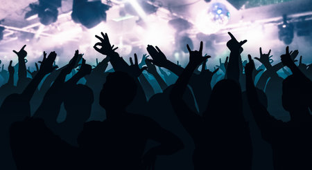 Silhouettes of dancing people in club in front of bright stage lights - disco concept