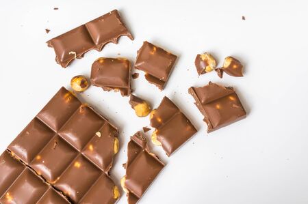 Broken chocolate bar with nuts isolated on white - top viewの写真素材