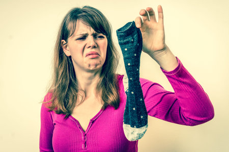Woman holding dirty stinky socks - unpleasant smell concept - retro styleの写真素材