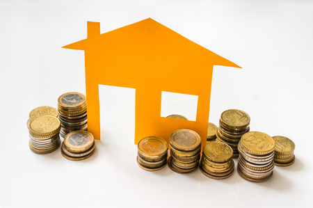 Paper house and stack of coins isolated on white backgroundの写真素材