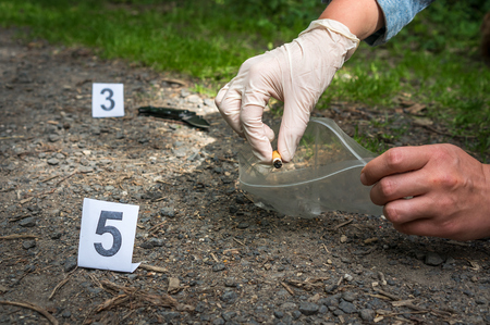 Investigator collects evidence (cigarette butt) - crime scene investigationの写真素材