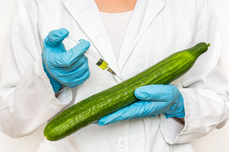 GMO scientist injecting liquid from syringe into cucumber - genetically modified food conceptの写真素材