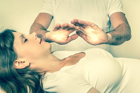 Young woman having reiki healing treatment - alternative medicine concept - retro styleの写真素材