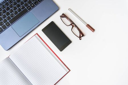 Workplace with laptop, smartphone, pen and blank notepad on white wooden table - overhead viewの写真素材