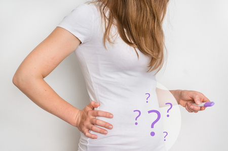 Unhappy woman with imagination of a pregnant belly holding negative pregnancy test - infertility conceptの写真素材