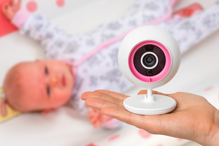 Hand of mother is holding baby monitor camera for safety of her cute babyの写真素材