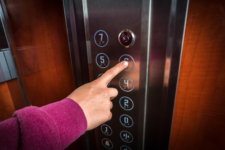 Woman pressing the button in the modern elevator interiorの写真素材