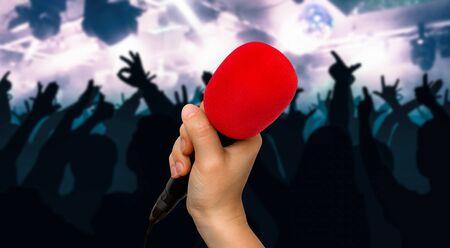 Hand of woman with red microphone and silhouettes of dancing people - music festival conceptの写真素材