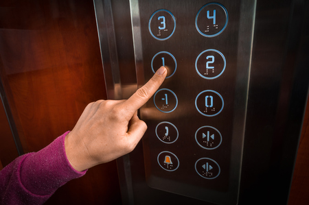 Woman pressing the button in the modern elevator interiorの写真素材