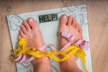 Female feet on personal scales with word HELP! - obesity and diet conceptの写真素材