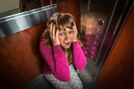 Shocked woman with claustrophobia in the moving modern elevatorの写真素材